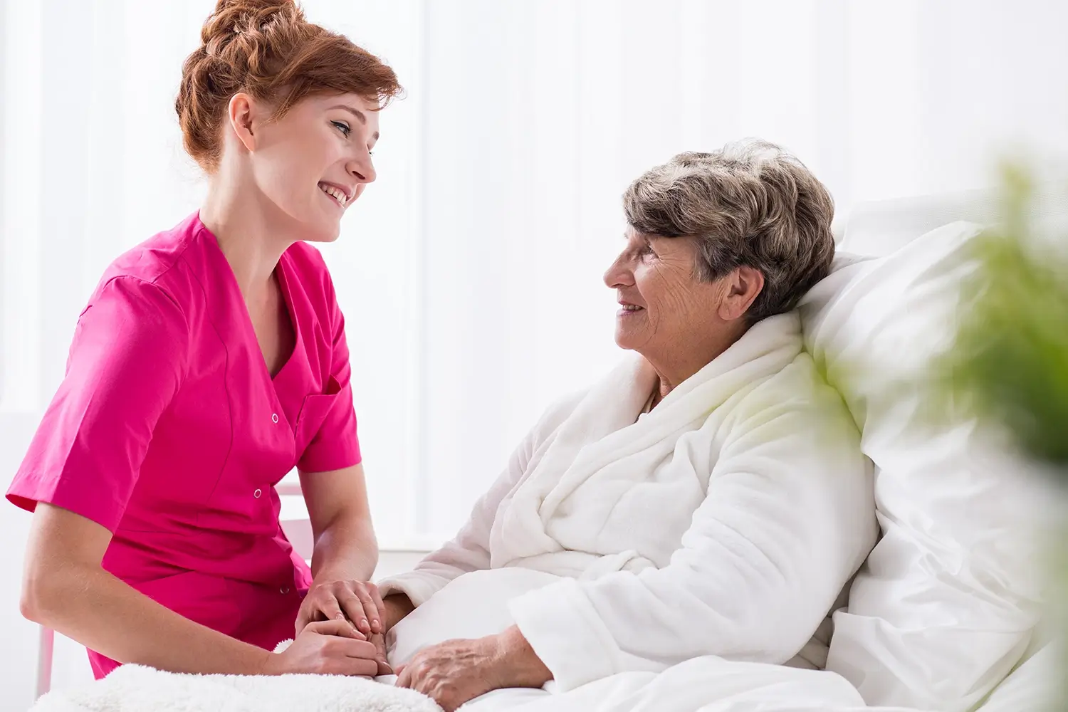 Eine lächelnde Krankenschwester unterhält sich mit einer glücklichen älteren Frau
